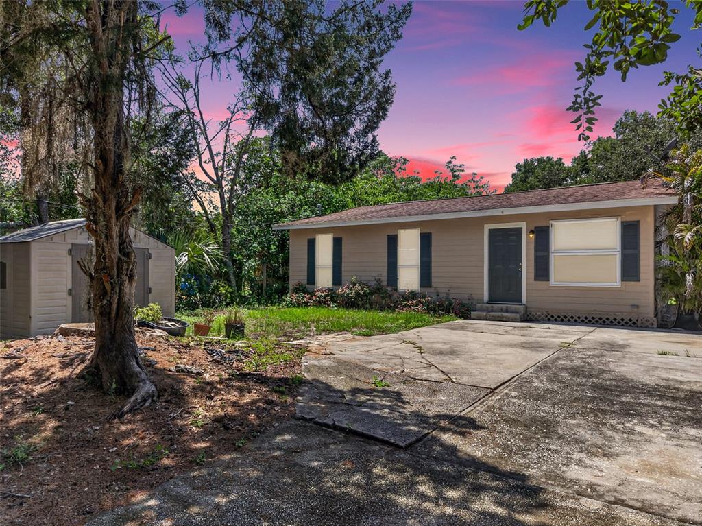 A tan single-story house with a concrete driveway and a small storage shed — 4793 PLEASANT AVENUE, PALM HARBOR, FL