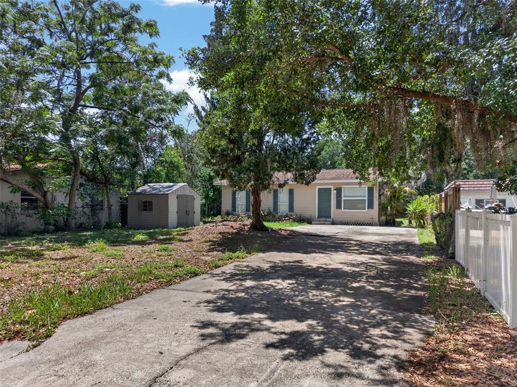 A single-story house with a concrete driveway, a storage shed, and mature trees in front — 4793 PLEASANT AVENUE, PALM HARBOR, FL