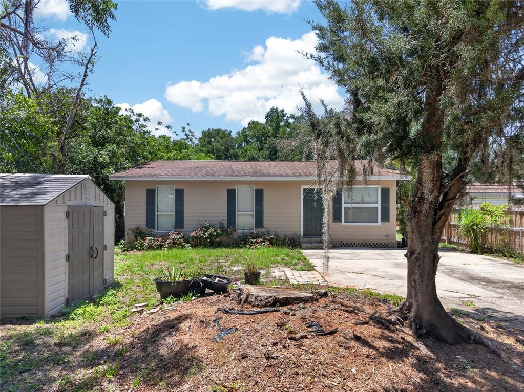 A single-story tan house with dark shutters, a front driveway, and a shed in the yard — 4793 PLEASANT AVENUE, PALM HARBOR, FL