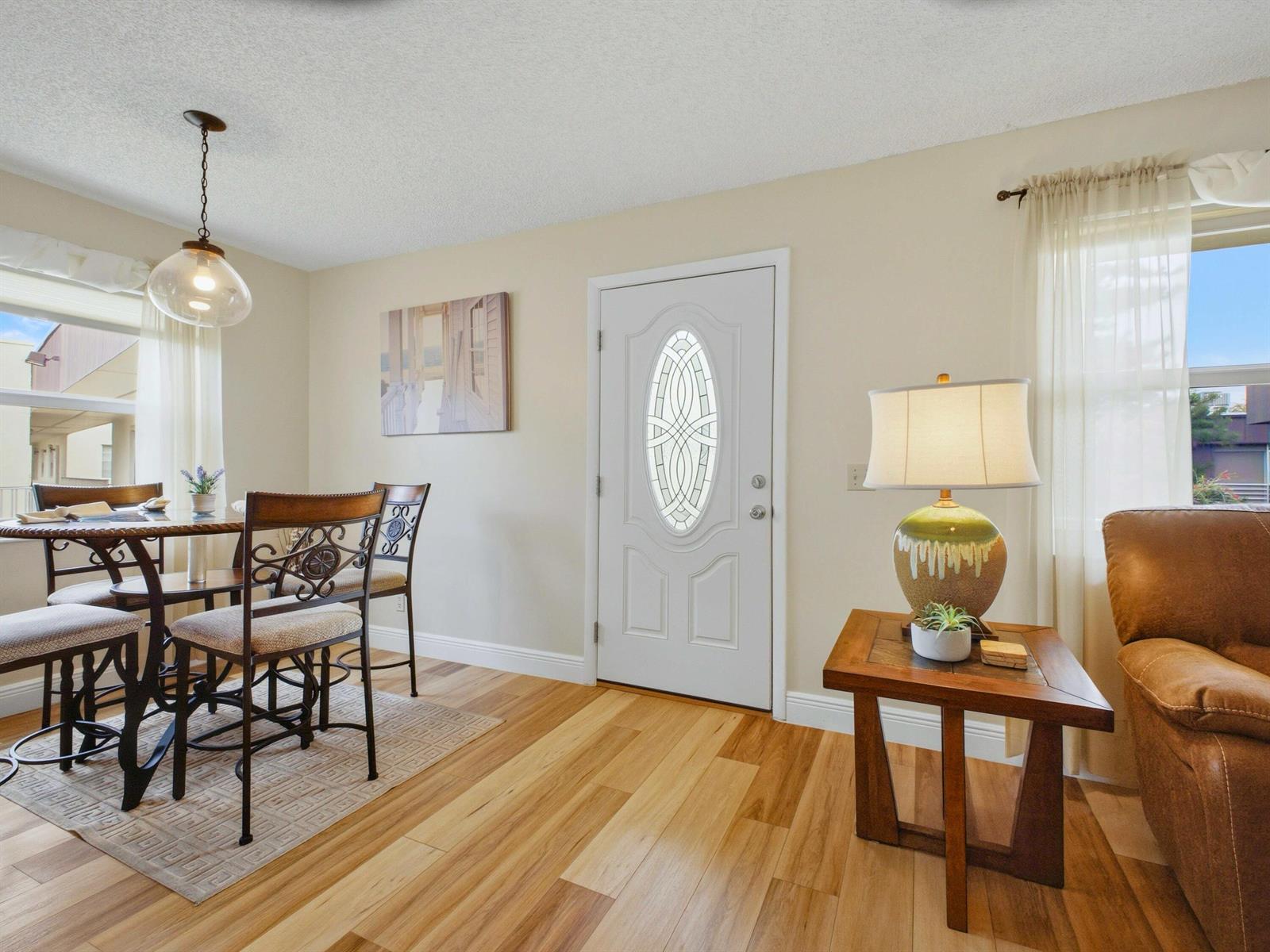 A dining area and entryway feature wood flooring, a white front door, and a table — 755 Normandy P, Delray Beach FL 33484, DELRAY BEACH, FL