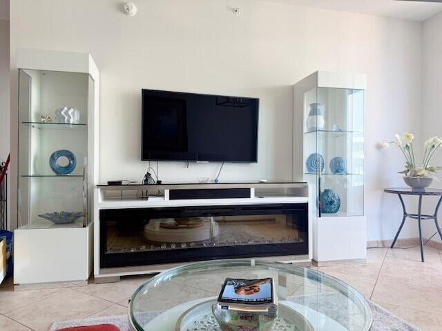 A living room features a wall-mounted television above a fireplace console flanked by glass cabinets — 625 Casa Loma Boulevard Unit 1, Boynton Beach FL 33435, BOYNTON BEACH, FL
