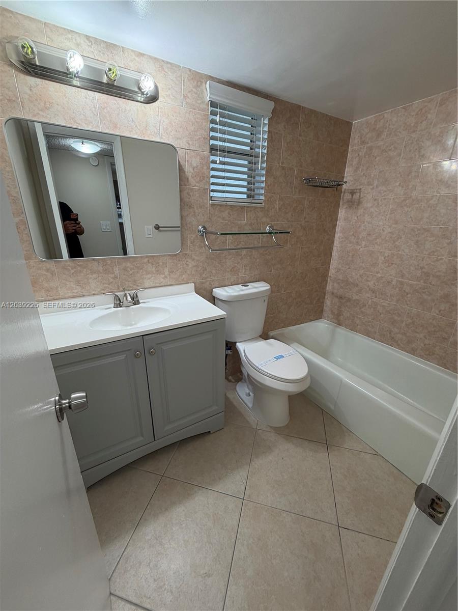 A bathroom features a gray vanity, a toilet, a bathtub, and tan tiled walls — 220 SW 9th Ave # 402, Hallandale Beach FL 33009, HALLANDALE BEACH, FL