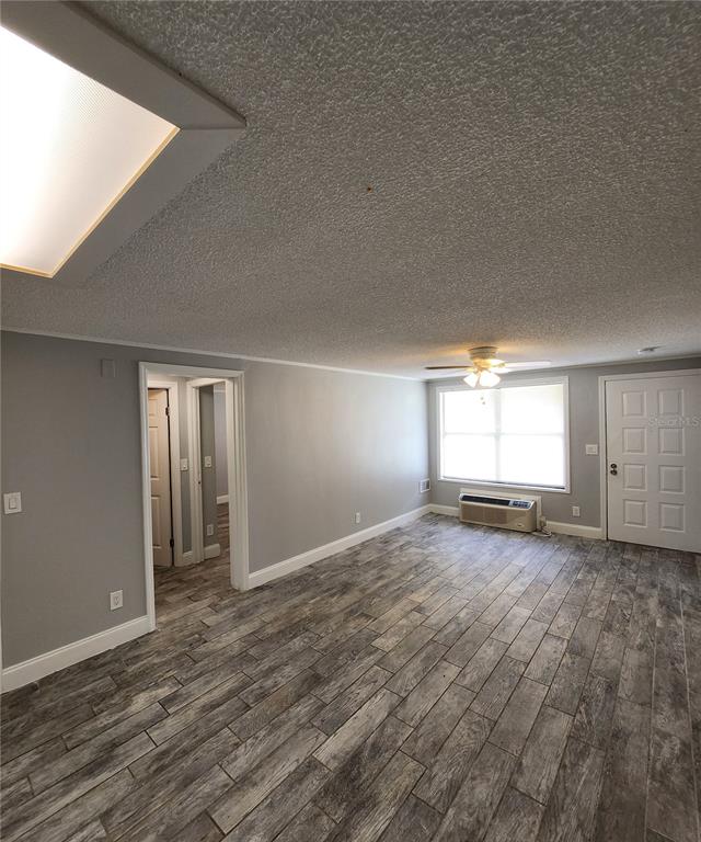 A living room with gray walls, wood-look tile flooring, a ceiling fan, and a window unit — 1400 STRAWBERRY PLACE UNIT 19, PLANT CITY, FL