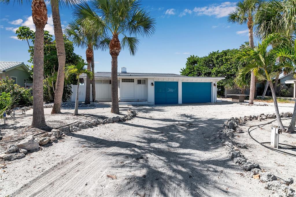 A one-story house with a white exterior and two blue garage doors sits on a lot — 2819 GULF OF MEXICO DRIVE, LONGBOAT KEY, FL
