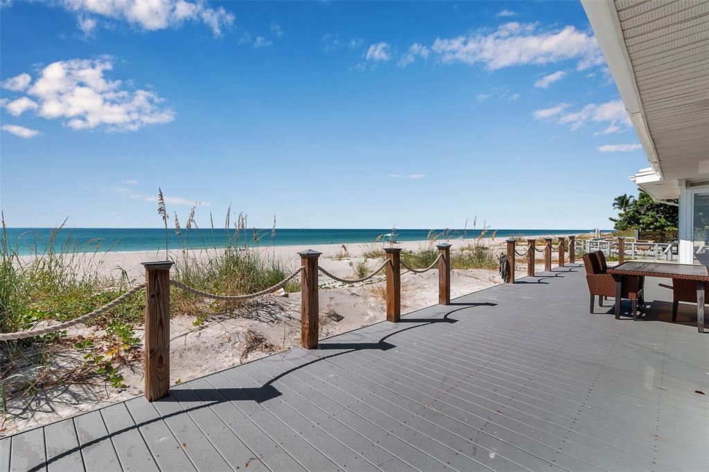 A gray wooden deck overlooks a sandy beach and the ocean under a blue sky — 2819 GULF OF MEXICO DRIVE, LONGBOAT KEY, FL