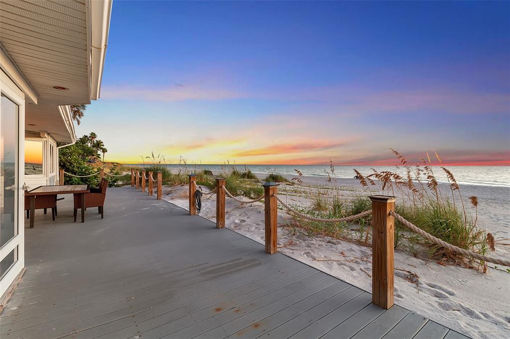 A wooden deck with rope railings overlooks a sandy beach at sunset — 2819 GULF OF MEXICO DRIVE, LONGBOAT KEY, FL