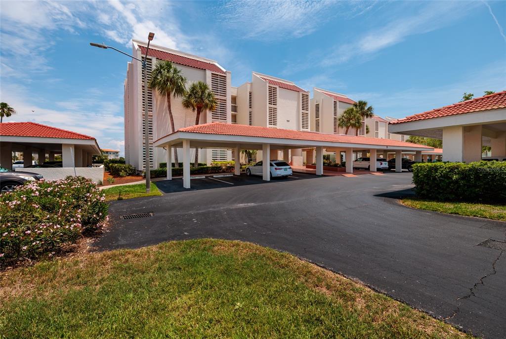 A multi-story residential building features a covered parking area with a red tile roof — 7897 SAILBOAT KEY BOULEVARD UNIT 107, SOUTH PASADENA, FL