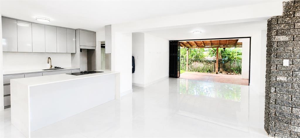 A modern kitchen with a white island and glossy floors opens to a covered patio — Urb Parkville AVE. LOPATEGUI, GUAYNABO, PR