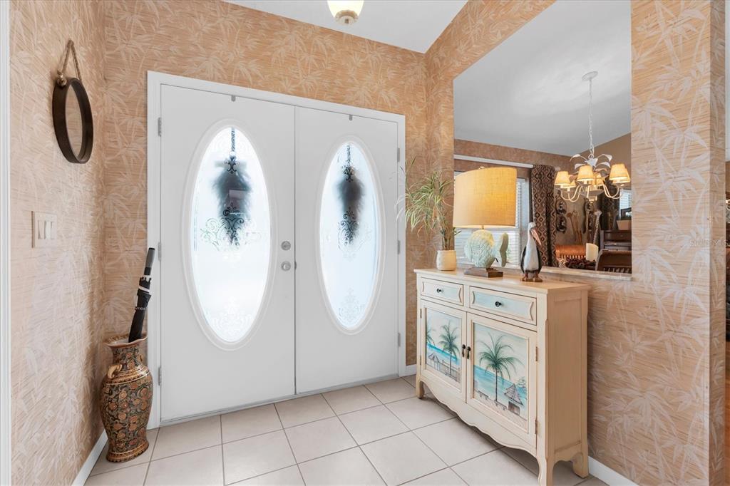 A living room features a vaulted ceiling, a large entertainment center, and sliding glass doors — 8388 OMAHA CIRCLE, SPRING HILL, FL