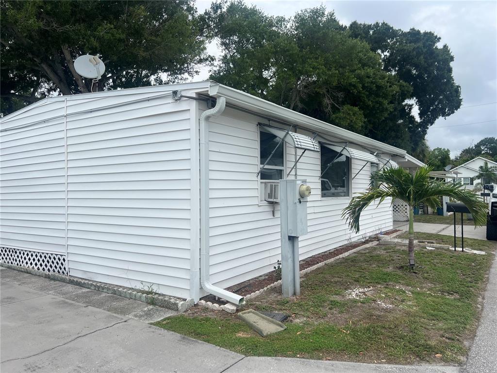 The exterior of a white mobile home features a metal utility pole and window awnings — 4772 67TH WAY N UNIT 51, ST PETERSBURG, FL
