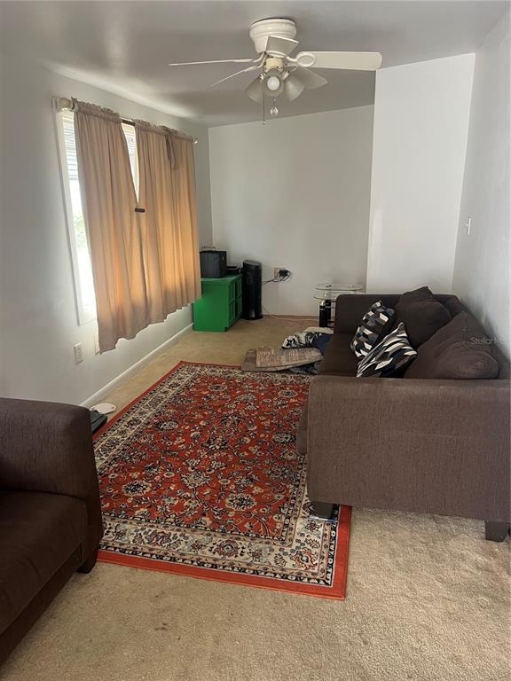 A living room features a brown sofa, a patterned area rug, and a ceiling fan — 4772 67TH WAY N UNIT 51, ST PETERSBURG, FL