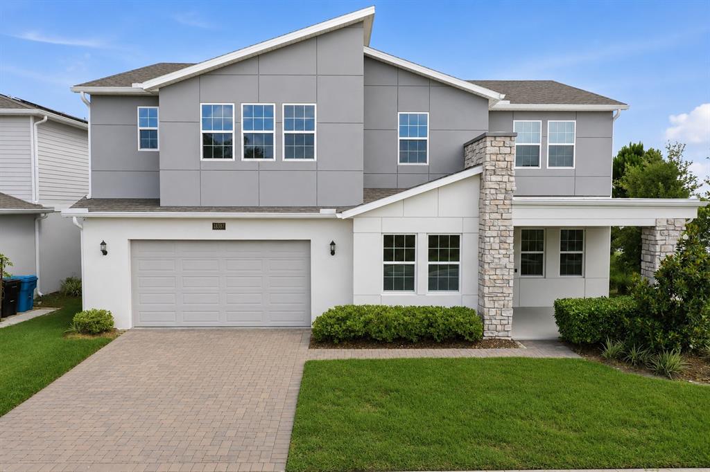 A two-story house features a gray and white exterior with a stone-accented entryway and garage — 18387 MOWRY COURT, ORLANDO, FL