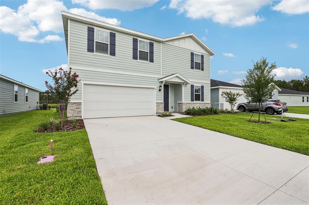 A two-story house with light green siding, a two-car garage, and a concrete driveway — 8 WANDERING CREEK WAY, PALM COAST, FL