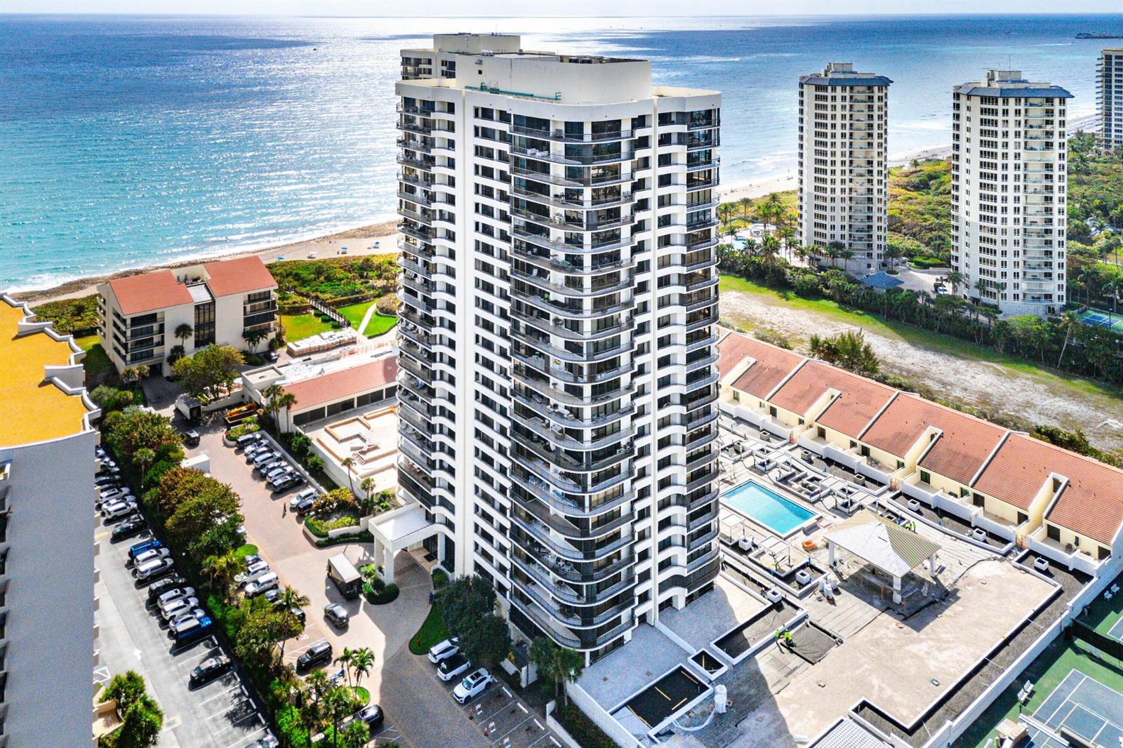 An aerial view shows a tall residential high-rise building situated near a beach and ocean — 4100 N Ocean Drive # 604, Singer Island FL 33404, SINGER ISLAND, FL