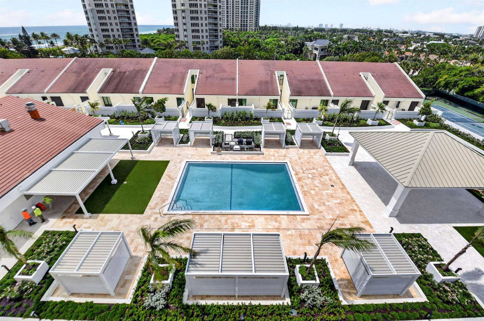 An aerial view of a swimming pool area with cabanas, landscaping, and a residential building — 4100 N Ocean Drive # 604, Singer Island FL 33404, SINGER ISLAND, FL