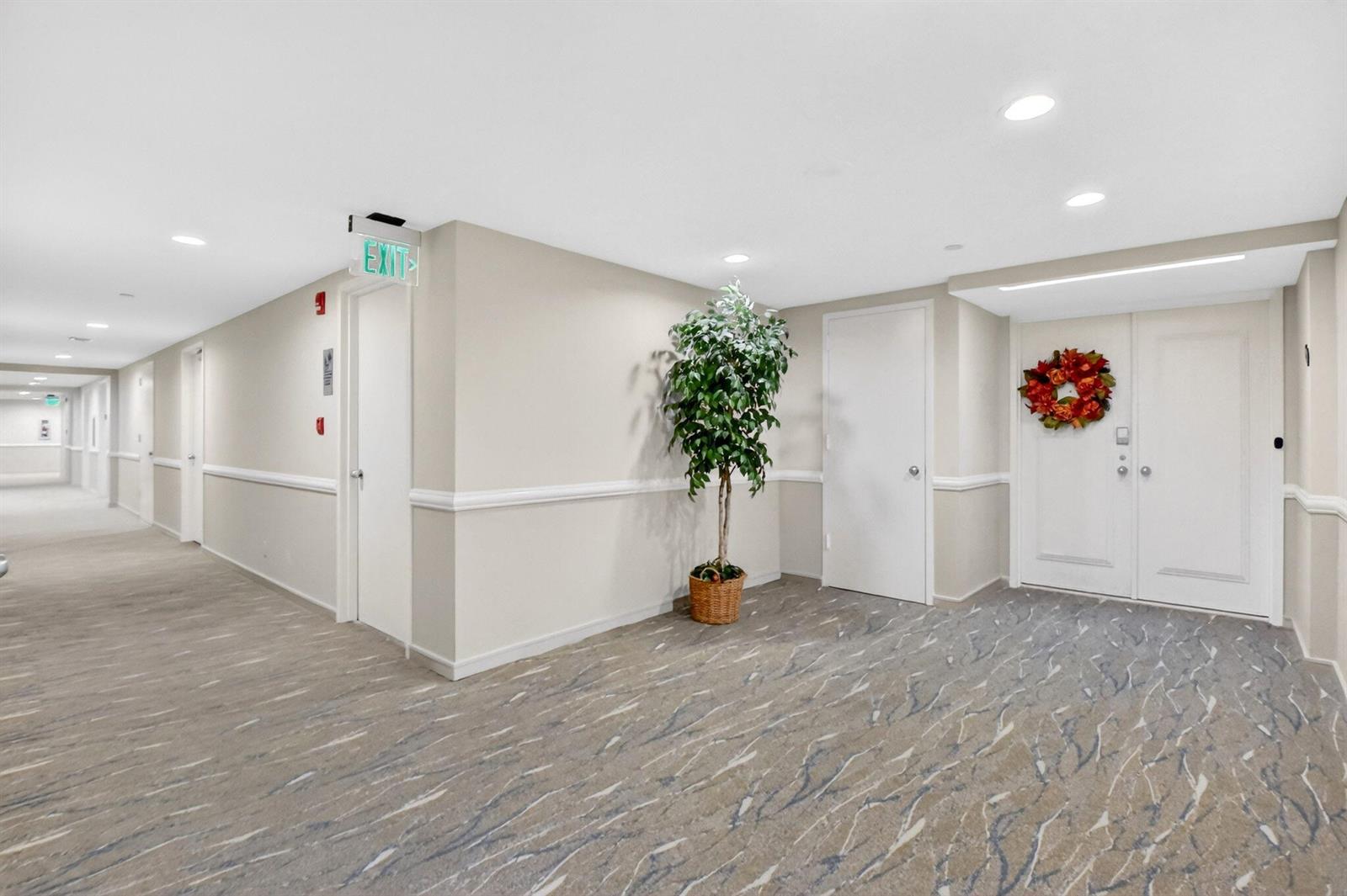 A hallway with beige walls, patterned carpet, a potted plant, and several white doors — 4100 N Ocean Drive # 604, Singer Island FL 33404, SINGER ISLAND, FL