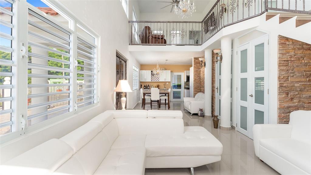 A bright living room features white leather sofas, tile floors, and a stone accent wall — Carr 411 Km 0.3 SECTOR RUIZ BO. CALVACHE, RINCON, PR