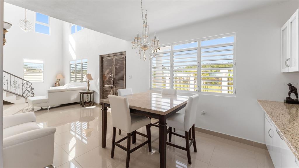 A bright dining area features a stone table, chandelier, and tile floors near a living room — Carr 411 Km 0.3 SECTOR RUIZ BO. CALVACHE, RINCON, PR