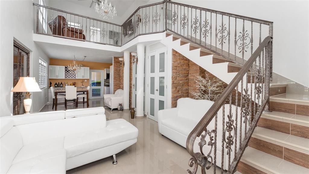 A living room with a white sectional, a staircase with decorative railings, and an open kitchen — Carr 411 Km 0.3 SECTOR RUIZ BO. CALVACHE, RINCON, PR