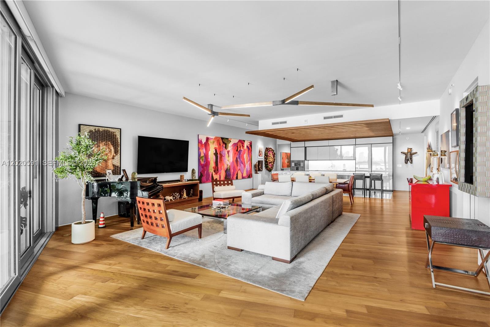 A spacious living room features hardwood floors, a large sectional sofa, and modern light fixtures — 1300 Monad Ter # 3E, Miami Beach FL 33139, MIAMI BEACH, FL