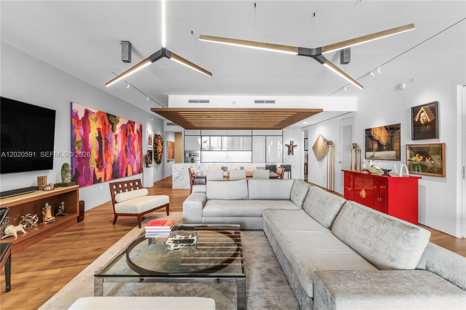 A modern living room features a large sectional sofa, glass coffee table, and abstract art — 1300 Monad Ter # 3E, Miami Beach FL 33139, MIAMI BEACH, FL