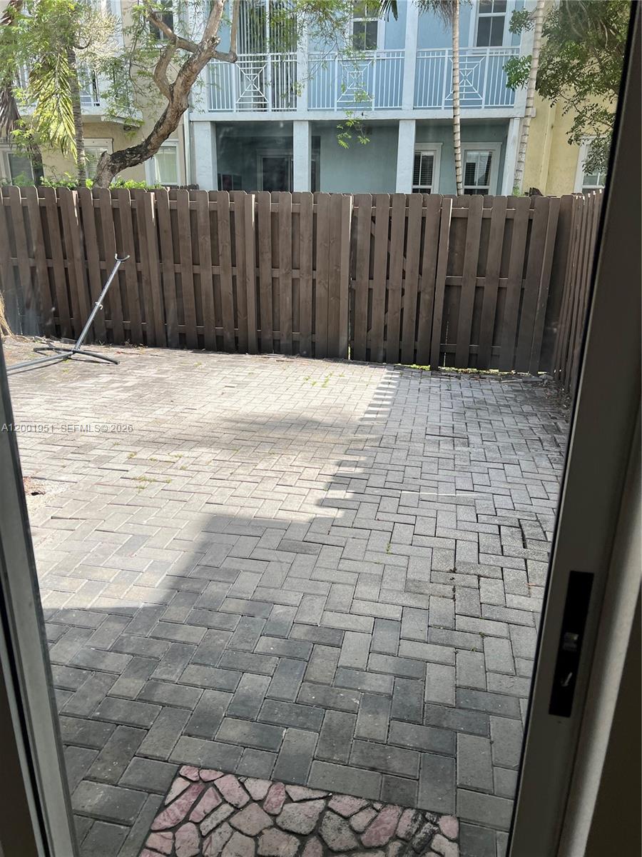 A paved patio area is enclosed by a wooden fence behind a multi-story building — 11440 NW 75th Ter, Doral FL 33178, DORAL, FL