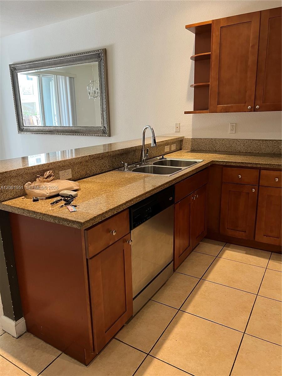 A kitchen features wood cabinets, granite countertops, a stainless steel dishwasher, and a double sink — 11440 NW 75th Ter, Doral FL 33178, DORAL, FL