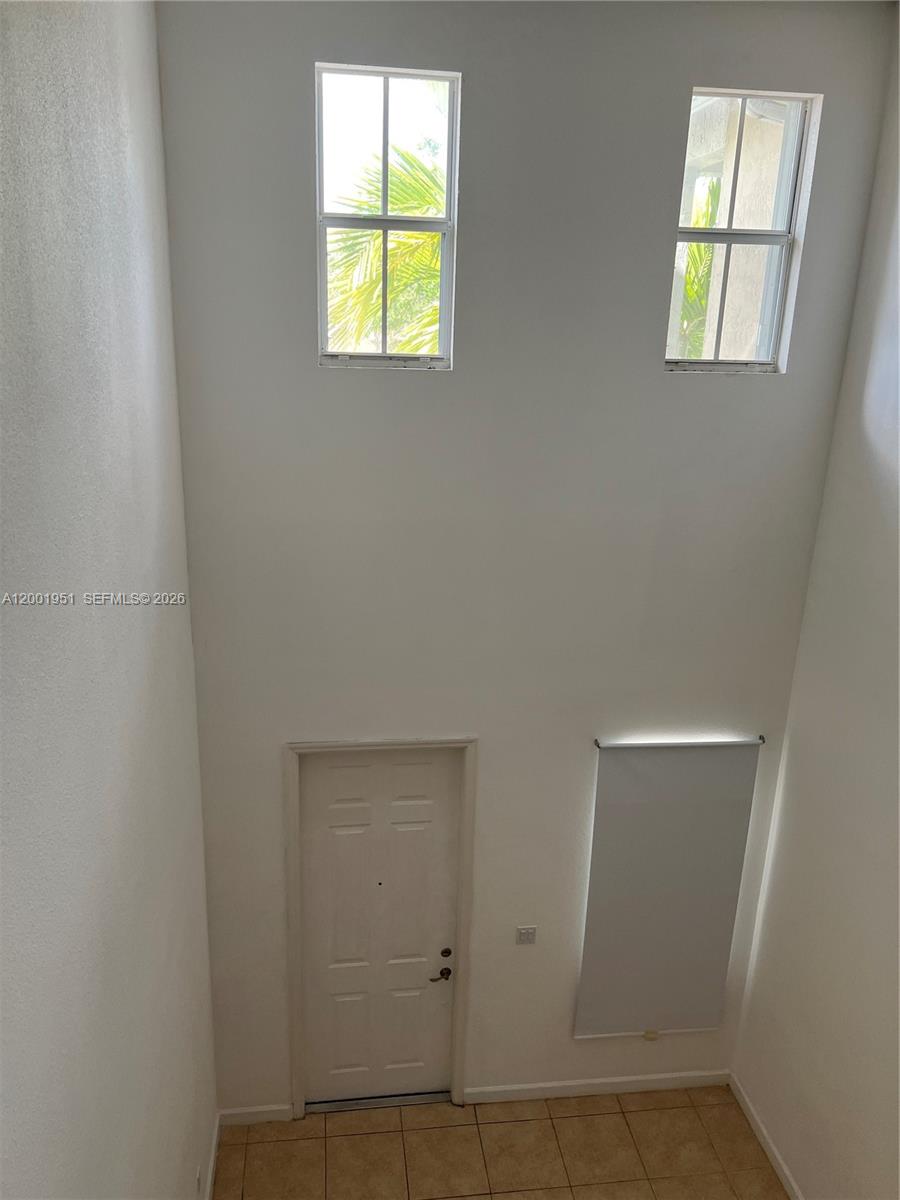 A high-ceilinged entryway features two upper windows, a white door, and tiled flooring — 11440 NW 75th Ter, Doral FL 33178, DORAL, FL