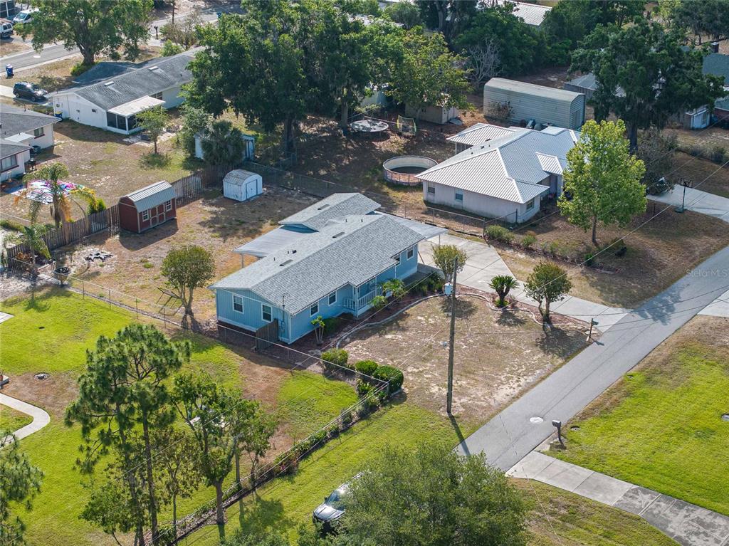 An aerial view shows a light blue house with a gray roof and a large yard — 729 E LAKE AVENUE, EAGLE LAKE, FL