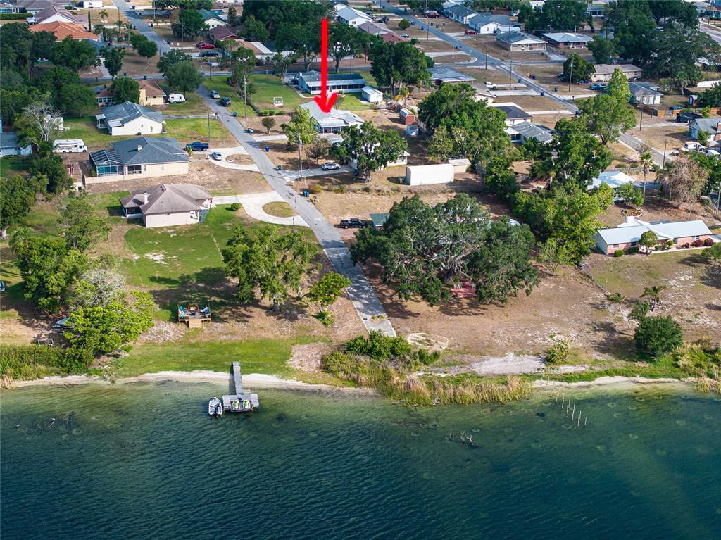 An aerial view shows a waterfront house with a private dock and a long driveway — 729 E LAKE AVENUE, EAGLE LAKE, FL
