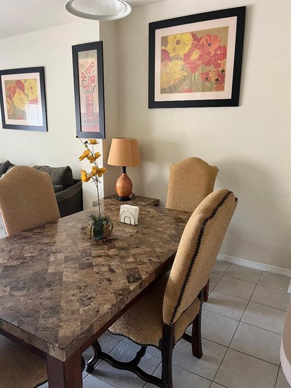 A dining area features a patterned stone table, upholstered chairs, and framed floral wall art — 4529 ALBERTO CIRCLE, KISSIMMEE, FL