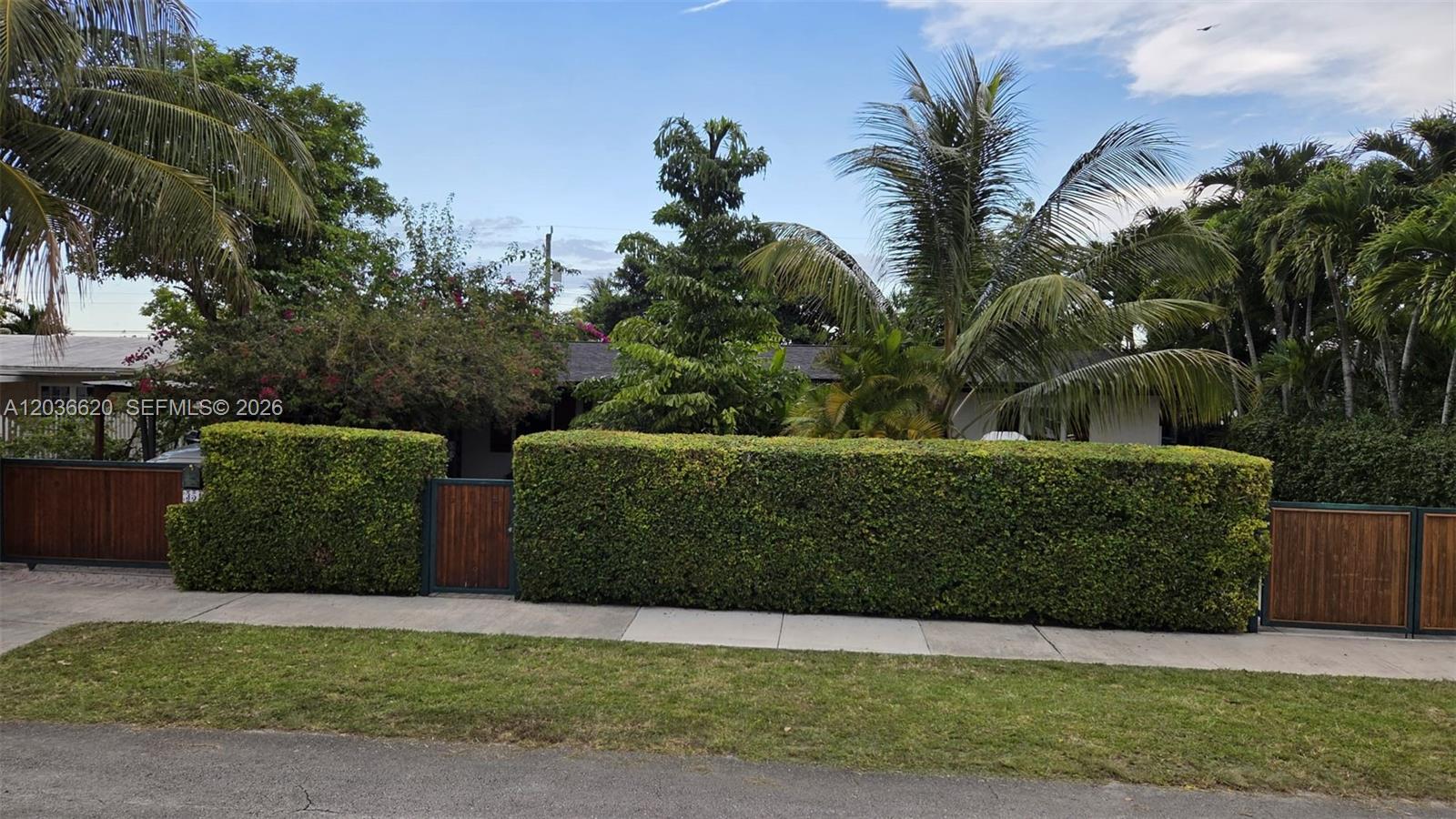 A house is obscured by a tall, manicured hedge and wooden gates — 3511 SW 105th ct, Miami FL 33165, MIAMI, FL
