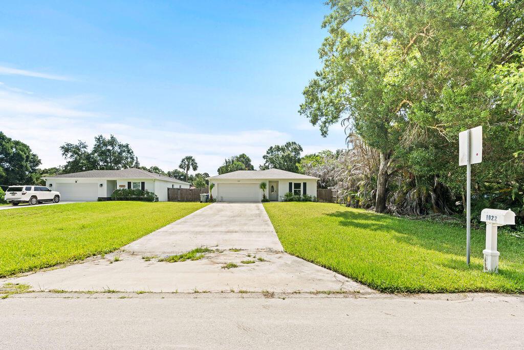 A single-story suburban house with a concrete driveway and a large tree in front — 1022 41st Avenue, Vero Beach FL 32960, VERO BEACH, FL