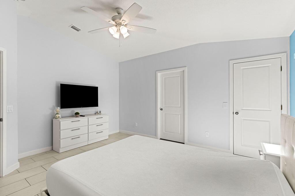 A bedroom features light blue walls, white tile flooring, a ceiling fan, and a white dresser — 1022 41st Avenue, Vero Beach FL 32960, VERO BEACH, FL