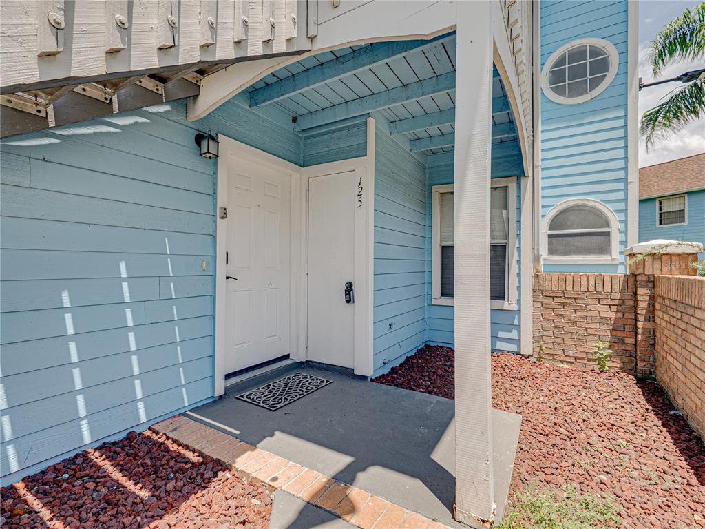 The exterior entrance of a light blue building features a white door and a small porch — 2729 N POINCIANA BOULEVARD UNIT 125, KISSIMMEE, FL