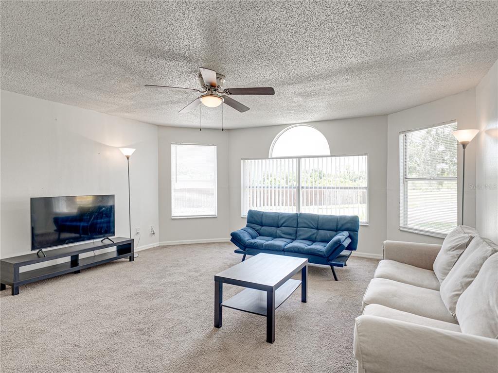 A living room features a blue futon, a white sofa, a coffee table, and a television — 2729 N POINCIANA BOULEVARD UNIT 125, KISSIMMEE, FL