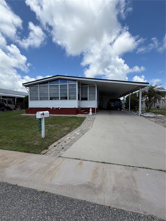 A white manufactured home features a brick base, a large front window, and a carport — 520 MARNIE CIRCLE, MELBOURNE, FL