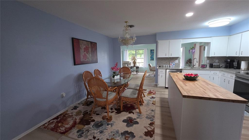 A dining area with a glass table and wicker chairs sits beside a kitchen island — 199 CADDY ROAD, ROTONDA WEST, FL