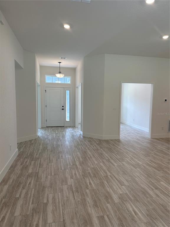 An entryway with light wood-look tile flooring leads to a white front door — 12126 PINE WARBLER AVENUE, BROOKSVILLE, FL