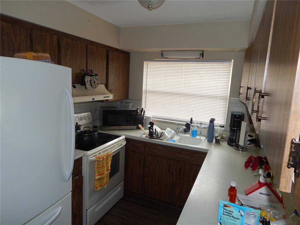 A galley kitchen features wood cabinets, white appliances, a double sink, and a window — 3509 LISA LANE, LAKELAND, FL