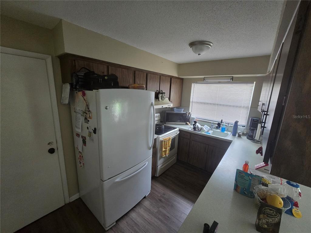 A kitchen features wood cabinets, a white refrigerator, a stove, and a window above the sink — 3509 LISA LANE, LAKELAND, FL