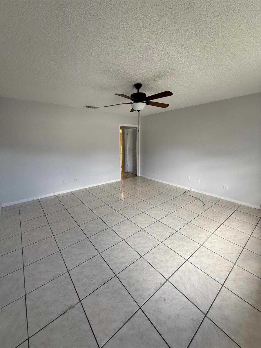 An empty room with light gray walls, white tile flooring, and a ceiling fan — 1201 White Pine Drive # 1201, Wellington FL 33414, WELLINGTON, FL