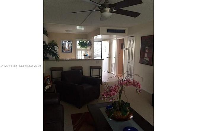 A living room features a dark armchair, a coffee table with orchids, and a ceiling fan — AVENTURA, FL