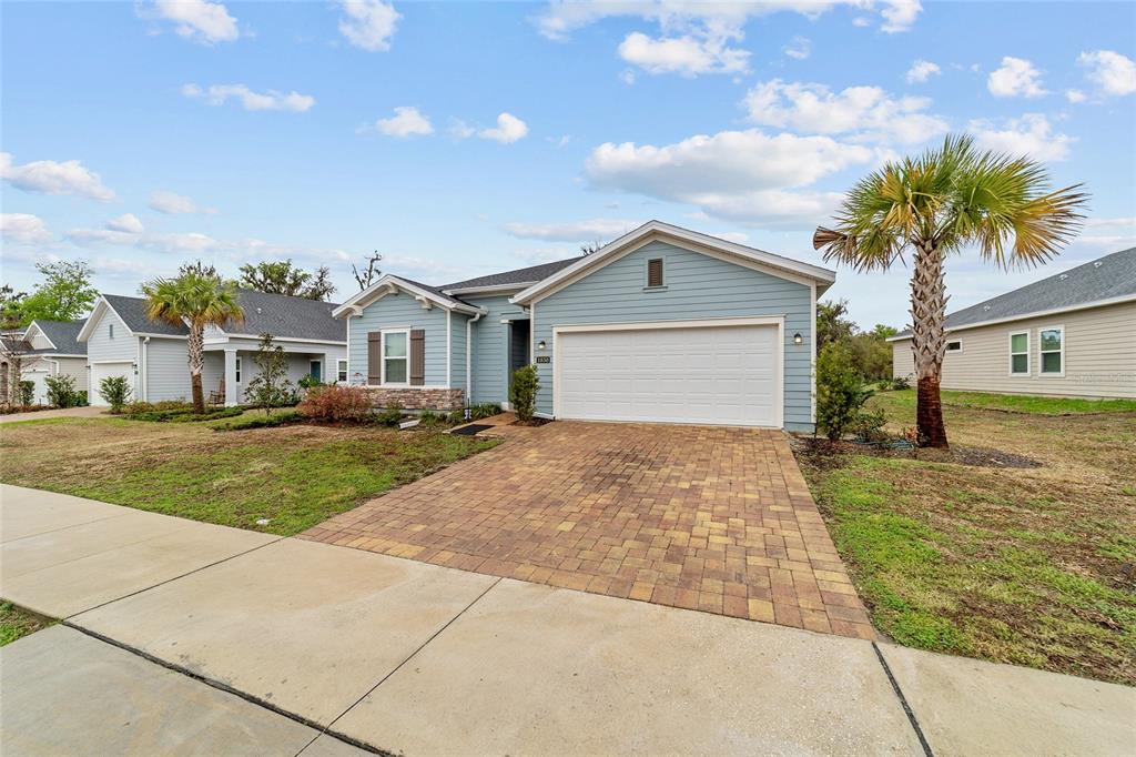 A light blue single-story house features a paved driveway, a two-car garage, and palm trees — 1830 NW 44TH COURT ROAD, OCALA, FL