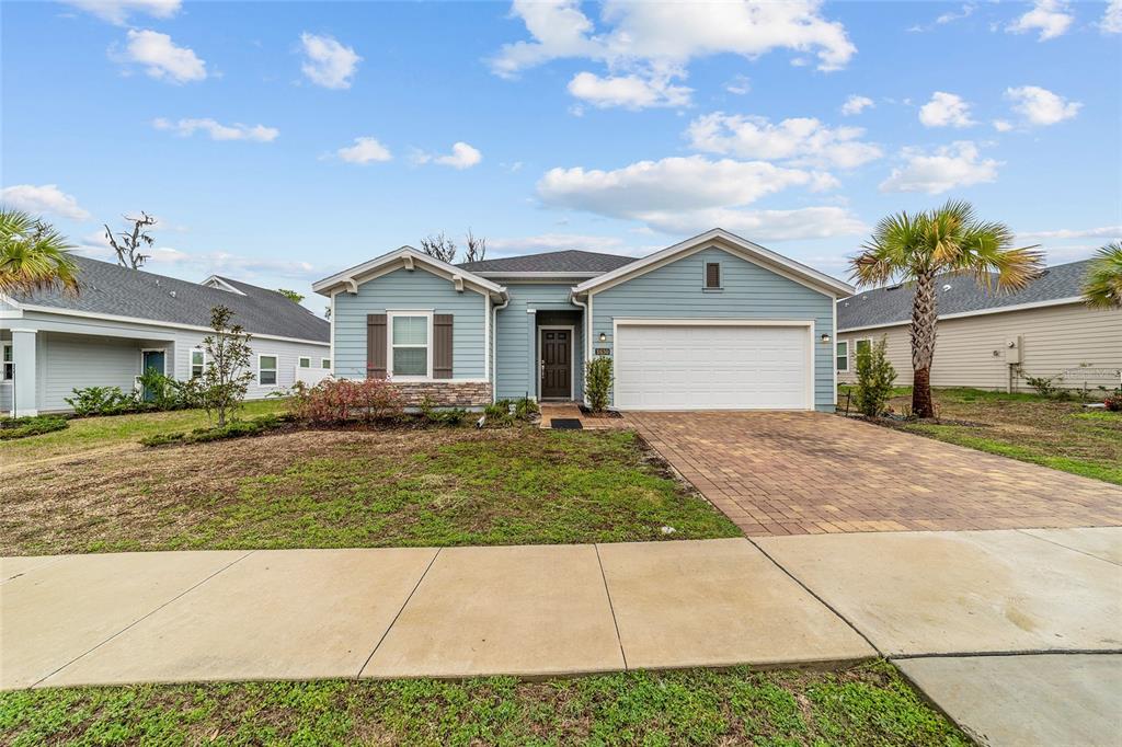 A single-story blue house with a two-car garage and a paved driveway — 1830 NW 44TH COURT ROAD, OCALA, FL