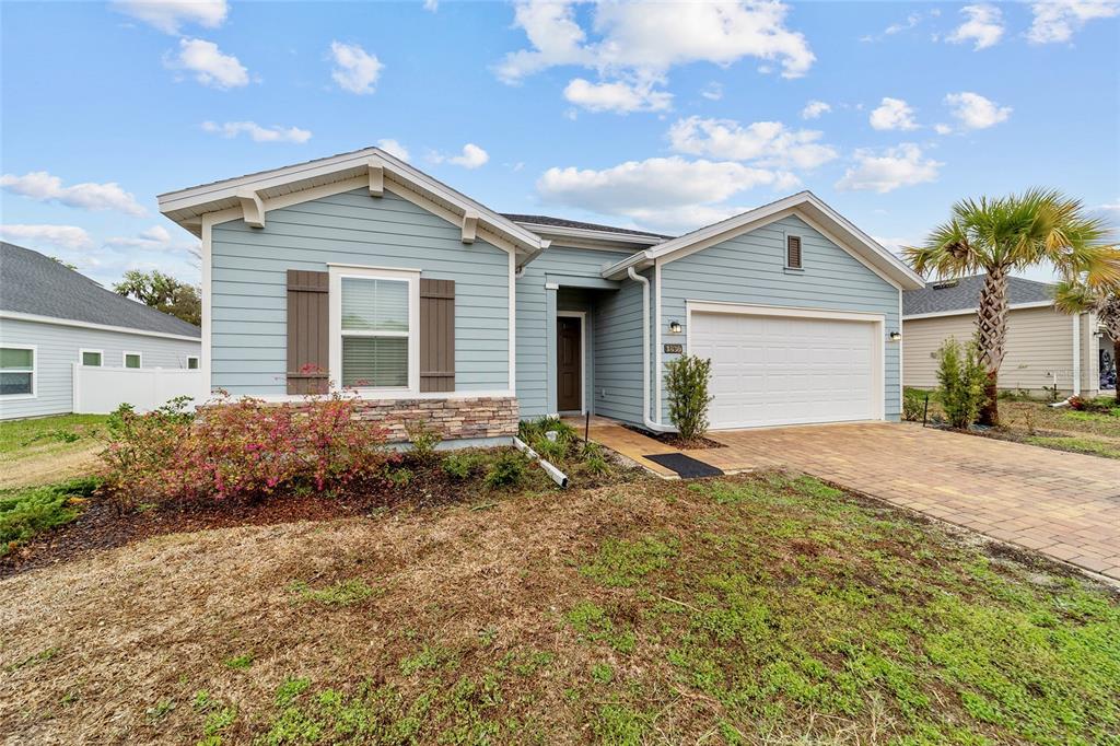 A light blue, single-story suburban house with a stone facade, shutters, and a paved driveway — 1830 NW 44TH COURT ROAD, OCALA, FL
