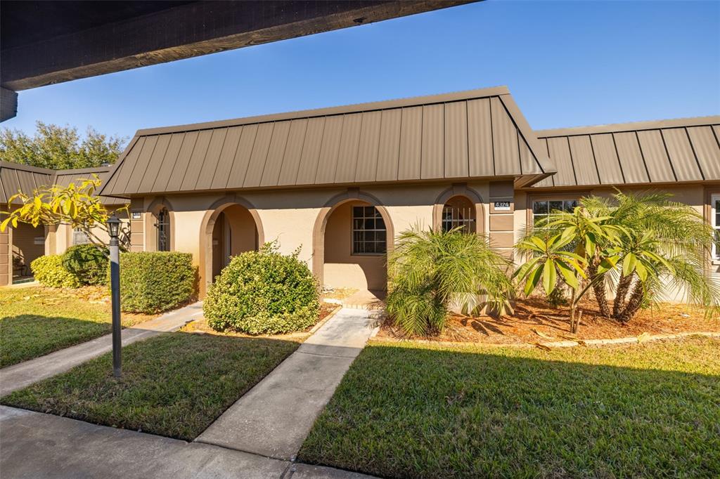 A single-story tan building with arched entryways and a dark metal mansard roof — 4324 SUMMERSUN DRIVE, NEW PORT RICHEY, FL