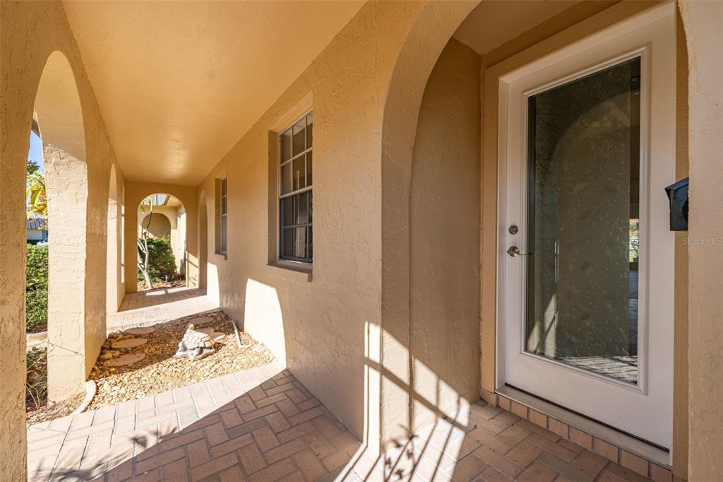 A covered entryway features arched openings, a paved walkway, and a glass-paneled front door — 4324 SUMMERSUN DRIVE, NEW PORT RICHEY, FL