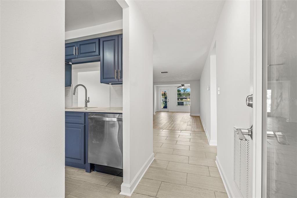 A view from a hallway looking into a kitchen with blue cabinets and a living area — 4324 SUMMERSUN DRIVE, NEW PORT RICHEY, FL