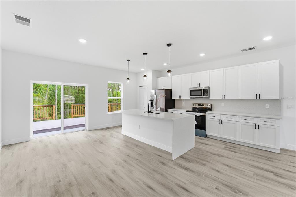 A bright kitchen features white cabinets, a central island, and light wood-look flooring — 785 MARION OAKS TRL UNIT 785, OCALA, FL